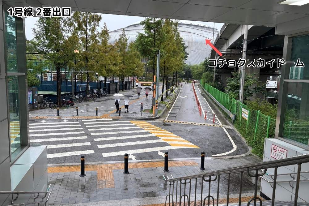 地下鉄1号線九一駅2番出口の階段から見た横断歩道と、右奥に見えるコチョクスカイドームの屋根
